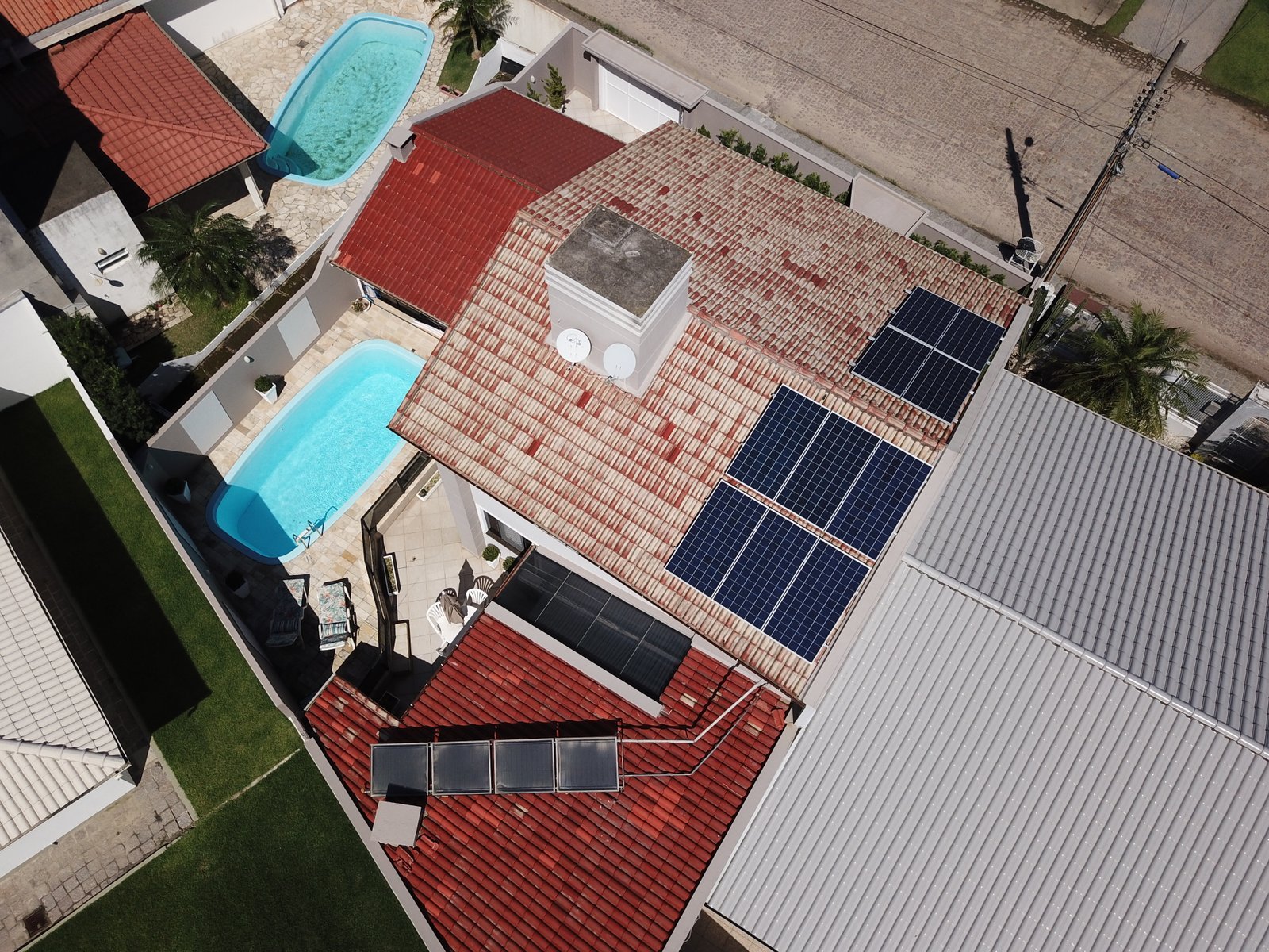 Casa com piscina e várias placas de energia solar instaladas nos telhados.